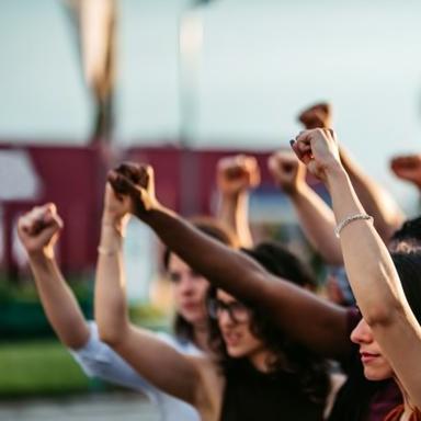Several people of different colors standing together with their fists up